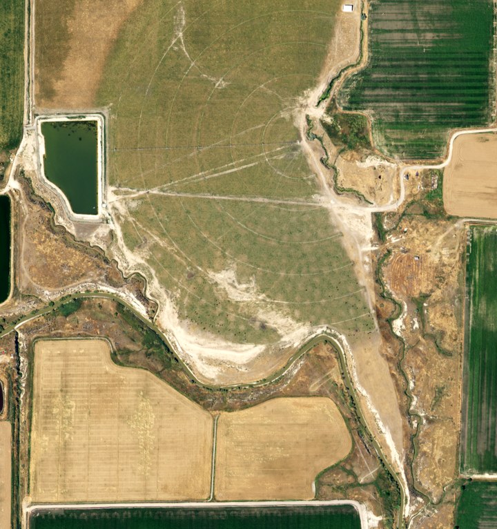 NAIP aerial photograph from 13 July 2016: a new reservoir at the top left, the field graded bare, and the curved wheel tracks of a center pivot already visible.